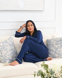 Woman in blue pajamas sitting on a white couch with floral cushions.